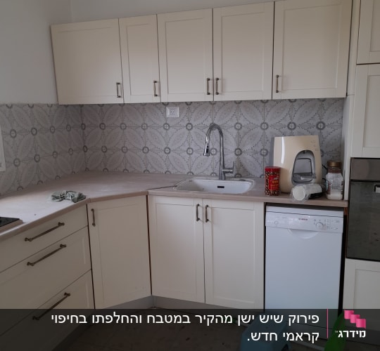 מטבח עם ארונות לבנים, כיור וכלי ניקוי על הרצפה